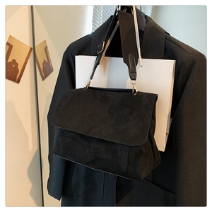 Détail du sac bandoulière en daim noir avec large sangle tissée bicolore sur veste