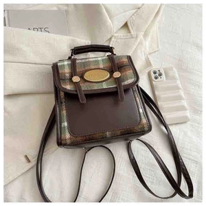 Detail of vintage plaid and brown leather mini backpack with golden logo and straps