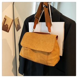 Gros plan d'un sac bandoulière en daim jaune gingembre avec large bandoulière