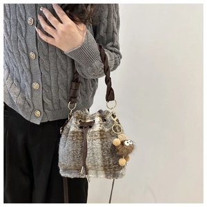 Detail of checkered tweed bucket bag with drawstring and cute monster pendant