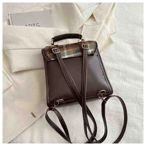 Detail of retro mini backpack featuring green and orange plaid flap with gold metal clasp