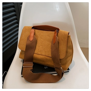 Détail du sac à rabat en daim moutarde avec boucle ronde et large bandoulière tissée
