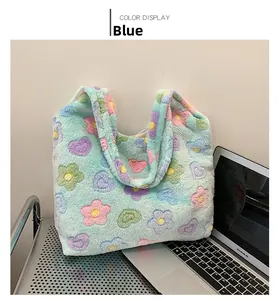 Detail of light blue fuzzy tote bag with colorful flower patterns on a laptop desk