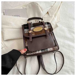 Detail of vintage contrast mini backpack featuring plaid fabric and gold metal emblem