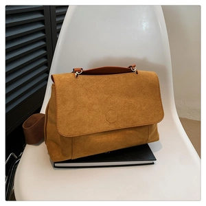 Détail d'un sac bandoulière en daim jaune gingembre avec une sangle marron