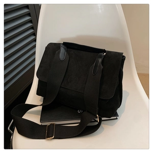 Détail de la texture du sac bandoulière en daim noir mat avec boucle réglable dorée
