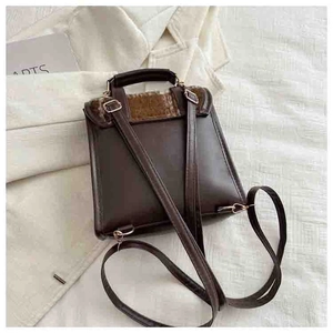 Detail of dark brown faux leather mini backpack with textured flap and gold hardware