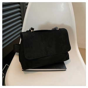 Détail du sac à bandoulière en daim noir avec anneau en métal doré et sangle tissée