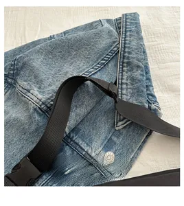Detail of light blue denim fabric with black nylon strap and metal jeans button closure