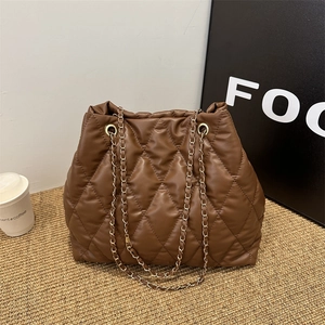 Sac fourre-tout matelassé en similicuir marron avec chaînes dorées sur tapis tissé