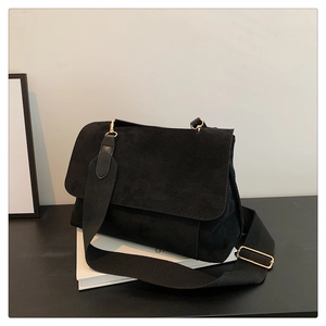 Détail du sac bandoulière en daim noir avec large sangle et crochets dorés en métal