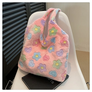 Detailed view of pink plush tote bag with colorful floral and heart pattern on a chair