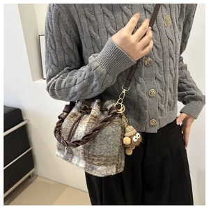 Detail of vintage plaid wool bucket bag with woven handle and cute bear charm accessory