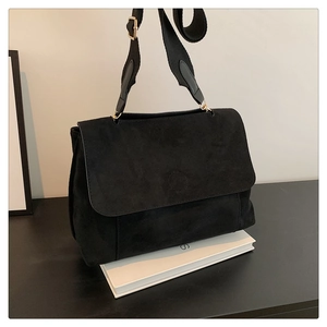Détail d'un sac bandoulière en velours noir avec rabat et bandoulière large tissée
