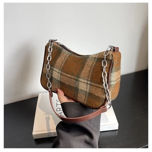 Detail of vintage brown plaid wool fabric texture and leather edging of the baguette bag