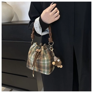 Detail of vintage wool plaid bucket bag with woven handle and plush monster charm