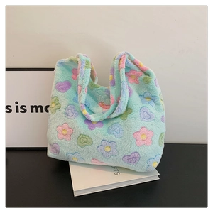 Detail of mint green plush tote bag featuring colorful floral and heart embroidery