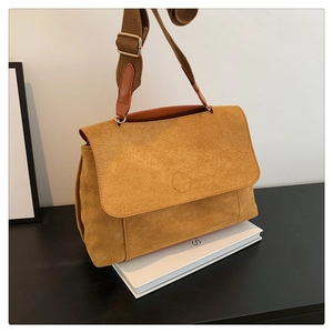 Détail de la sacoche en daim jaune moutarde avec bandoulière large en tissu texturé