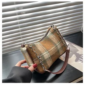 Close-up of tricolor plaid tweed shoulder bag with silver chain and leather strap details