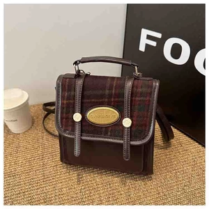 Close-up of vintage mini brown backpack with red plaid flap and gold metal hardware