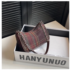 Detailed view of plaid underarm bag with silver chain and brown leather strap