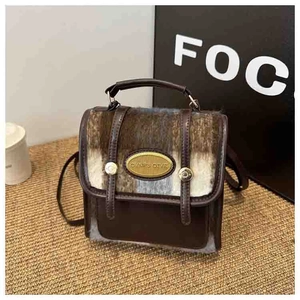 Detail of contrast stitching and gold metal logo on brown plaid faux fur crossbody bag