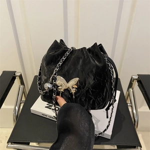 Sac seau noir chic avec texture plissée et boucle papillon argentée sur bandoulière
