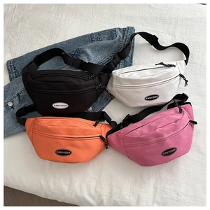 Nylon dumpling fanny pack in black, white, orange, and pink colors on denim jacket background