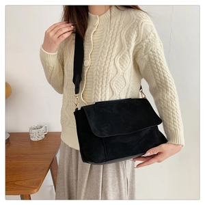 Détail du sac bandoulière en daim noir avec large sangle en tissu et crochets dorés