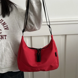 Waterproof red nylon crescent crossbody bag with adjustable strap shown on model