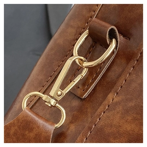 Close-up of golden metal hook and stitching on brown vintage leather bucket bag