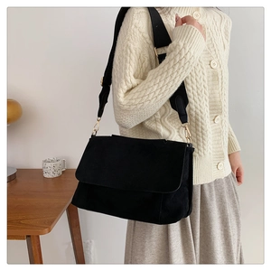 Détail du sac bandoulière en daim noir avec large sangle et boucle en métal doré chic