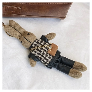 Detail of creative knitted rabbit bag charm with houndstooth vest and leather pants decor