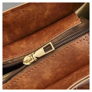 Close-up of vintage brown leather bucket bag with golden metal zipper detail