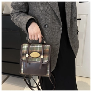 Detail of vintage mini crossbody bag featuring green plaid fabric and brown leather trim