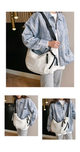 Detailed view of a white nylon crescent shoulder bag featuring black woven zipper details