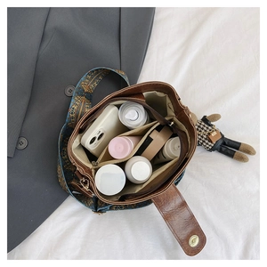 Detail view of brown bucket bag interior showing multiple compartments and ethnic woven strap