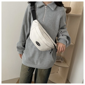 Detail of white canvas waist bag with adjustable black strap and brand logo patch