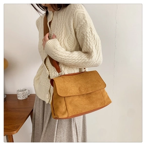Sac hobo minimaliste en daim camel avec large bandoulière porté par un mannequin