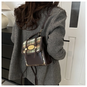 Detail of vintage wool plaid bucket bag with brown leather trim and metallic brand plaque