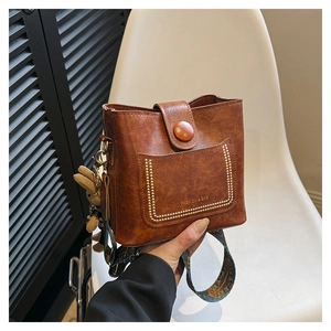 Detail of vintage brown bucket bag with wide woven strap and plush rabbit charm