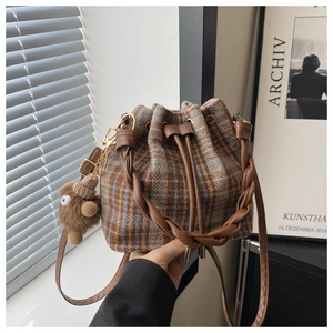 Close-up of vintage plaid tweed bucket bag with leather drawstring and woven handle