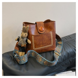 Detail of vintage brown bucket bag with gold studs and blue geometric strap
