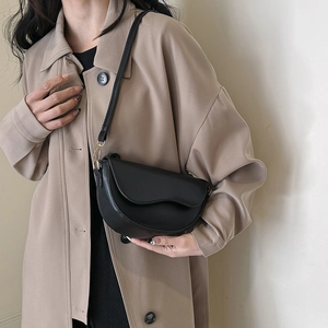 Détails du sac selle en cuir noir mat avec rabat ondulé et boucles dorées chic