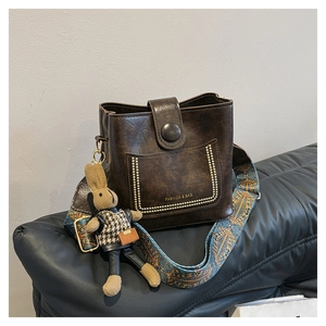 Detail of vintage dark brown bucket bag with gold rivets and ethnic pattern strap