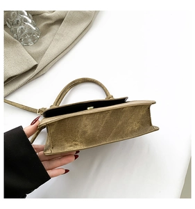 Detail of khaki denim crossbody bag showing its sturdy base and round metal handle