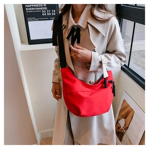 Detail of red nylon crescent crossbody bag with black strap and large knot zipper pull
