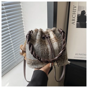Detail view of tweed drawstring bucket bag with leather strap and cute bear charm