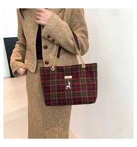 Close-up of tartan wool tote bag featuring a gold deer charm and metal chain strap