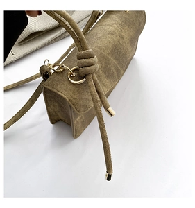Close-up of olive green crossbody bag featuring textured canvas and gold-tone knot hardware
